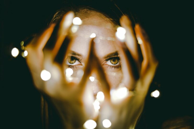 Image of a woman holding fairy lights in front of her face symbolizing ego defense mechanisms