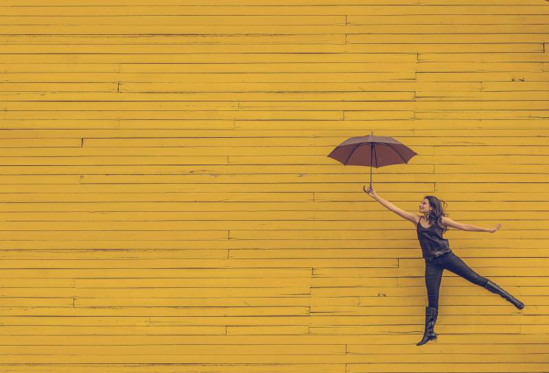 Image of an extroverted introvert woman with an umbrella dancing