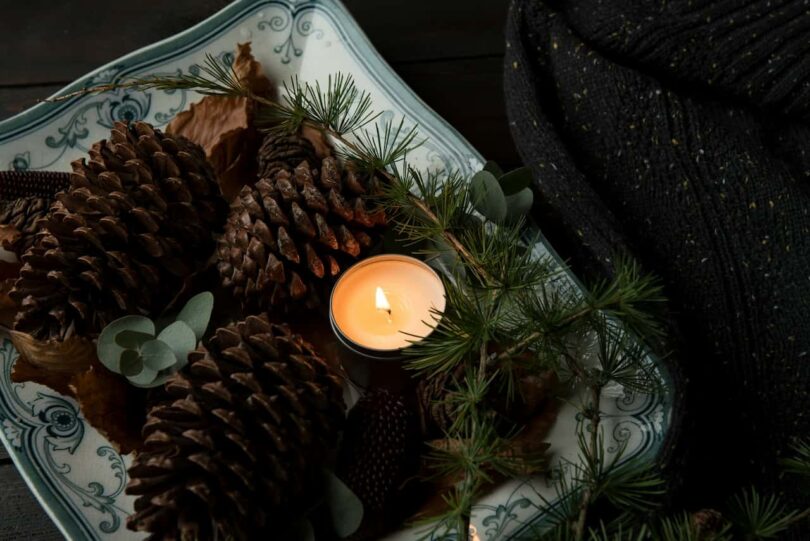 Image of a single Christmas candle among pine cones symbolic of spending Christmas alone
