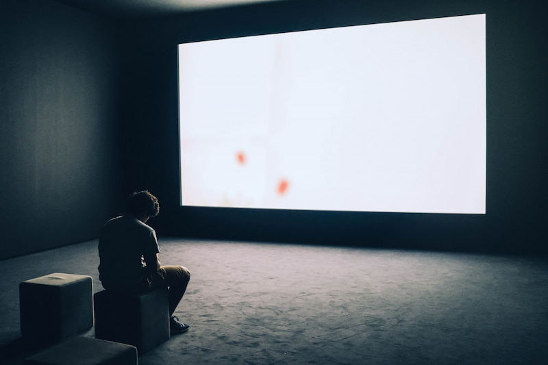 Image of a depressed man sitting alone watching a blank screen of the tv