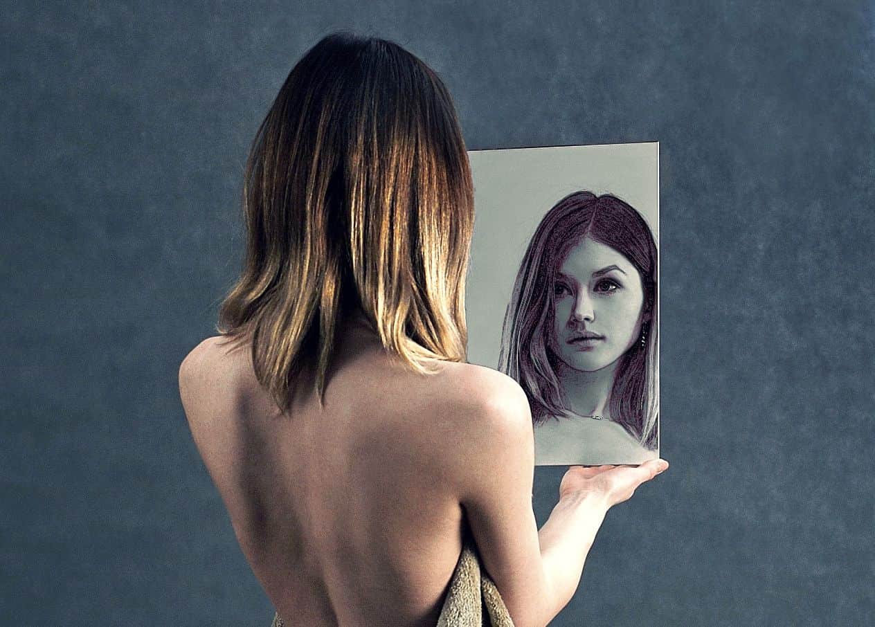 Image of a woman looking in the mirror being self-aware