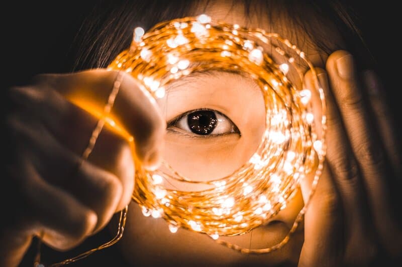 Image of a girl holding fairy lights to her eye