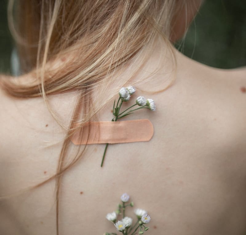 Image of a woman with flowers stuck to her back with bandaids symbolic of the victim mentality