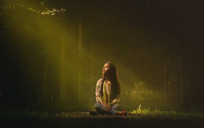 Image of a woman grounding herself in a forest