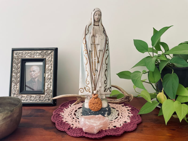 Image of an altar dedicated to the Divine Mother with a statue of her in the center with a plant on the side and a singing bowl on the other side
