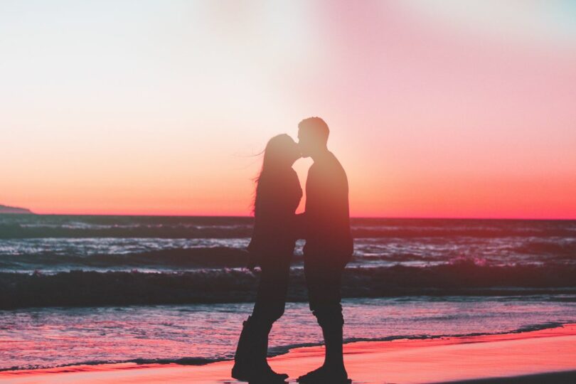 Image of a twin flame runner couple kissing on the beach
