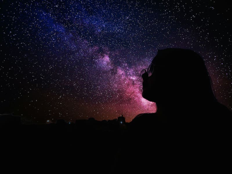 Image of a woman looking up at the cosmos sky