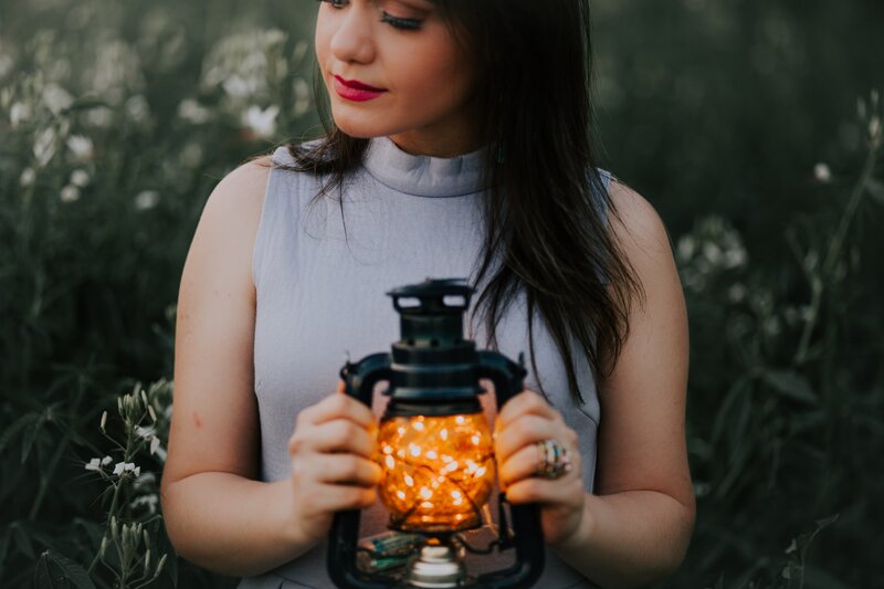 Image of a woman holding a lantern in a field of flowers