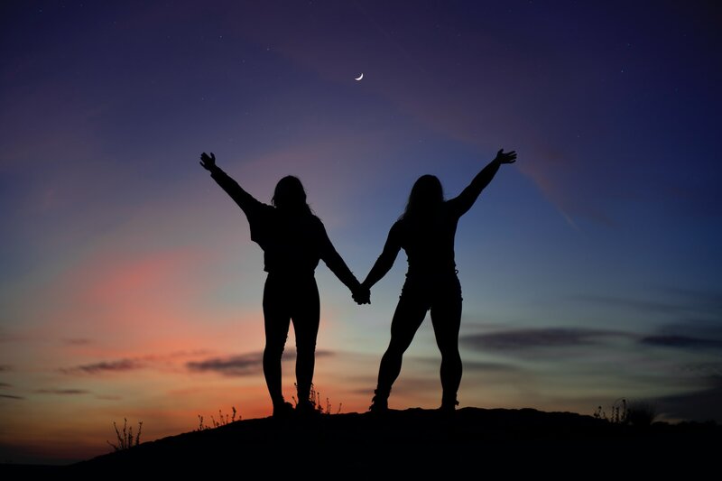 Image of two women standing together at sunset