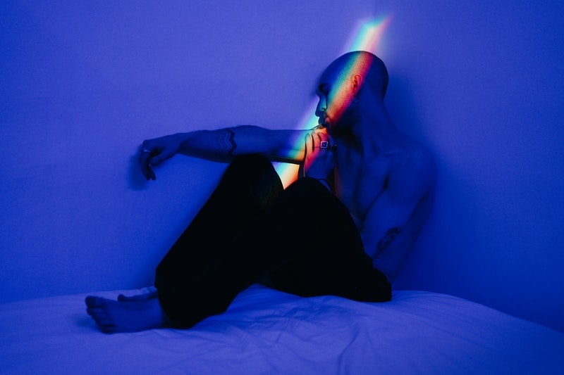 Image of a scared man in a dark room with rainbow light shining on his face