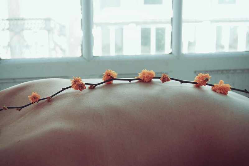 Image of a person's back with flowers laid on top during a healing session