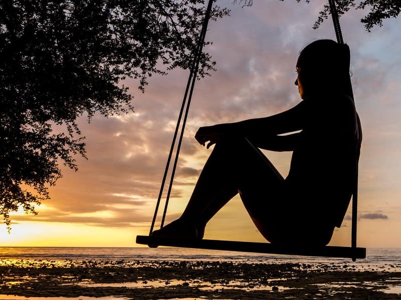 Image of a person sitting on a swing quietly learning how to trust their intuition