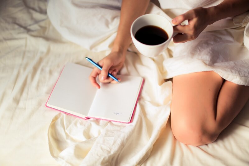 Image of a woman journaling on her bed