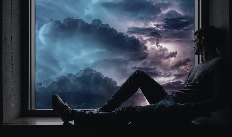 Image of a man brooding as he watches the dark sky