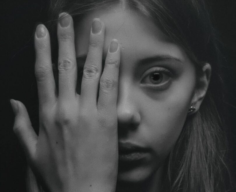 Image of a woman with her hand over her face experiencing emotional numbness