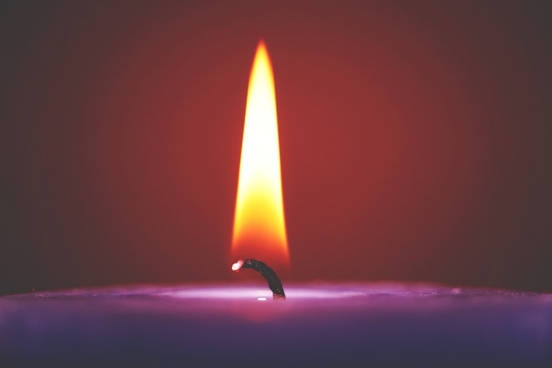 Image of a purple candle burning symbolic of spiritual healing