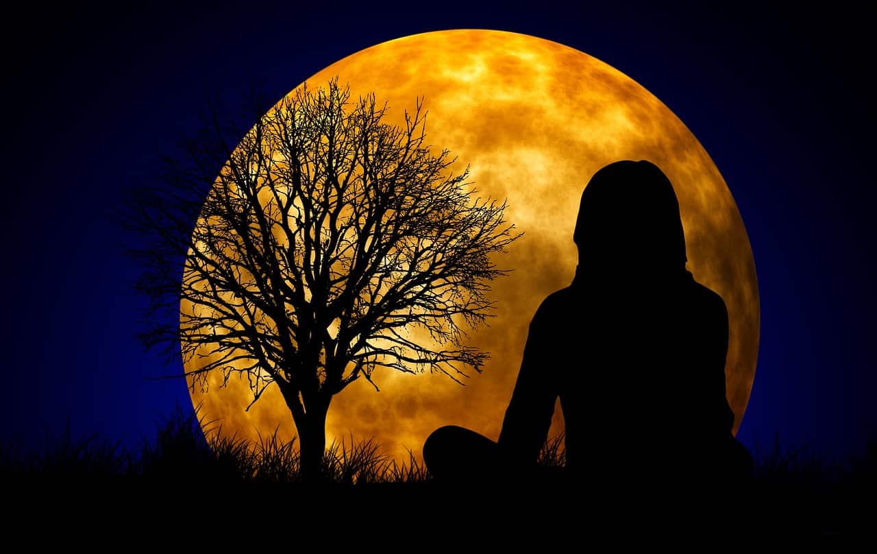 Image of a woman sitting in front of a moon experiencing oneness and wholeness