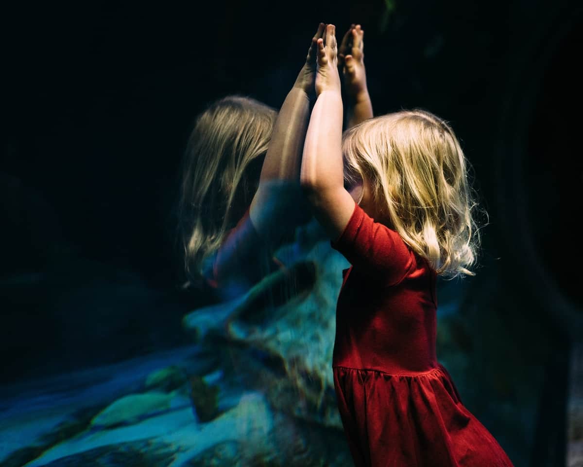 Image of a young girl looking at her reflection being self-aware