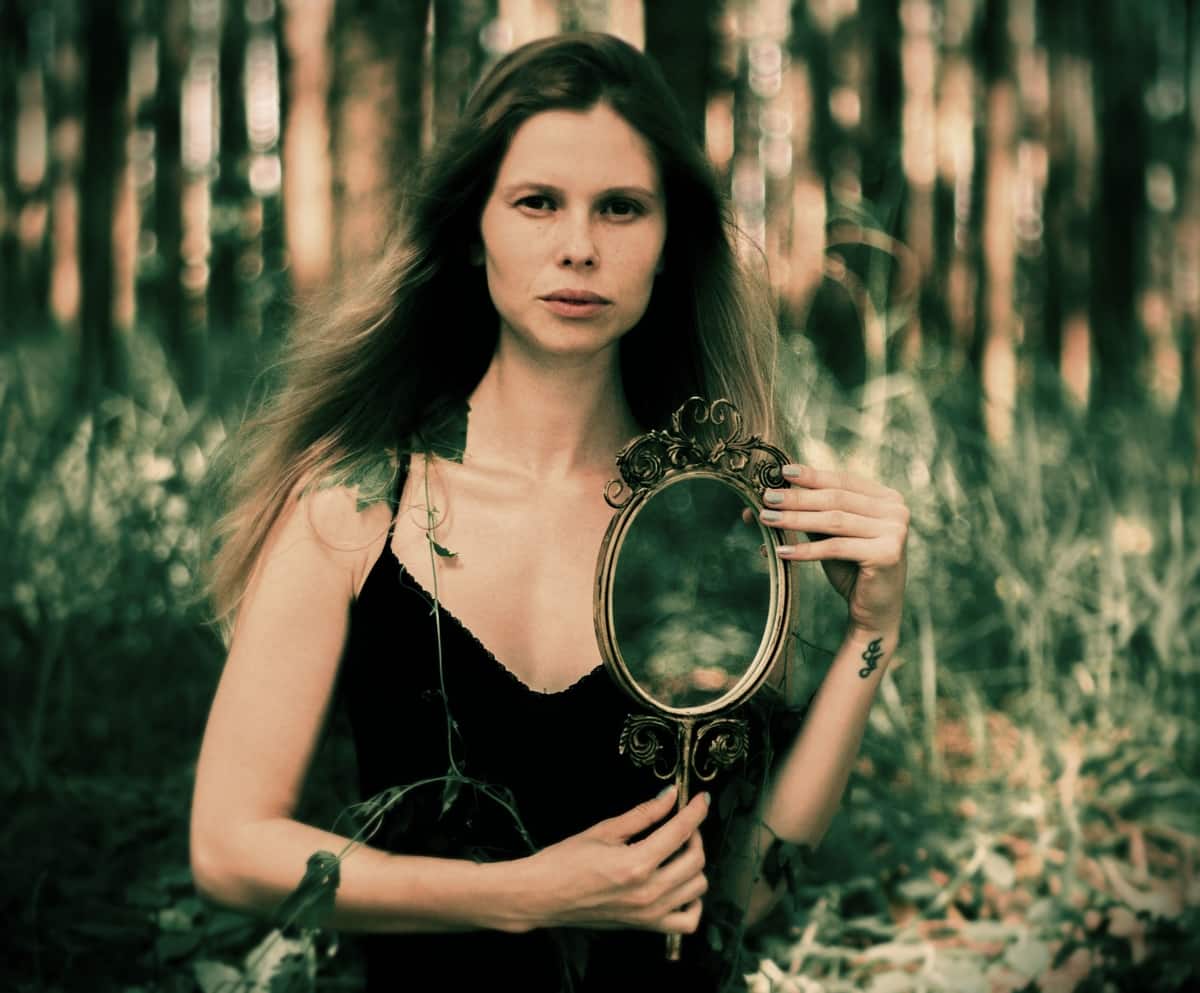 Image of a woman holding up a mirror symbolizing self-awareness