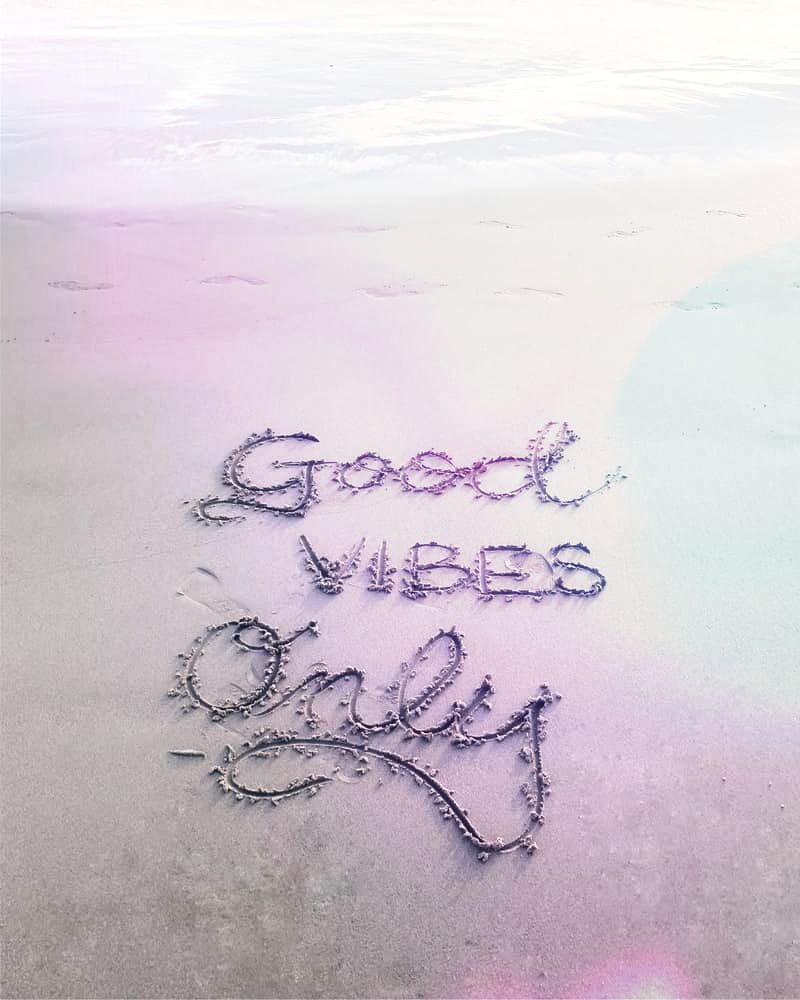 Image of good vibes only drawn into beach sand