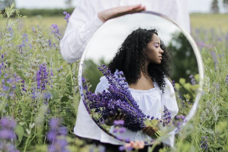 Image of a woman holding a mirror reflecting someone