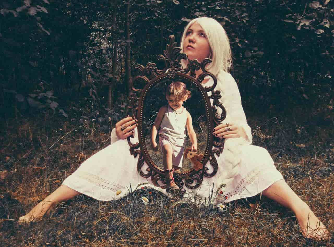 Image of a woman holding a mirror doing inner child work