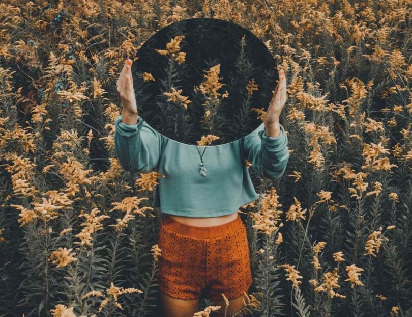 Image of a woman holding up a mirror doing mirror work