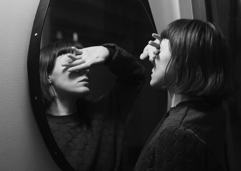 Image of a woman standing in front of a mirror feeling uncomfortable