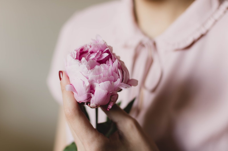 Image of a woman holding a pink peony flower