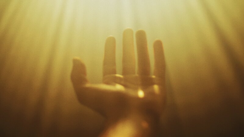 Image of a person's hand reaching out to the light for a meaning of life