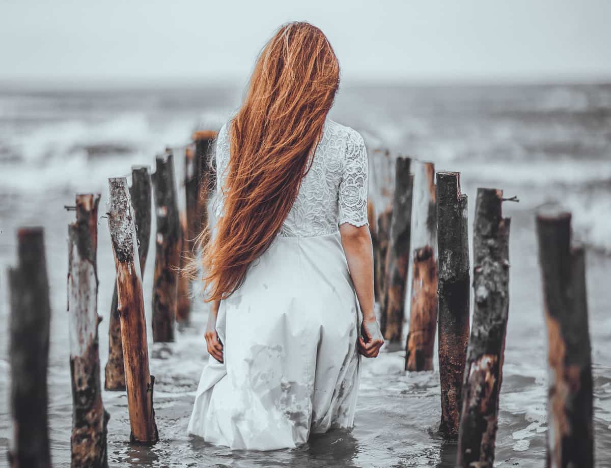 Image of a lonely woman walking into the ocean