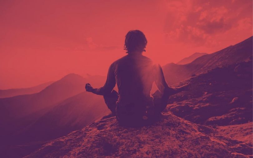 Image of a man meditating on a mountain top