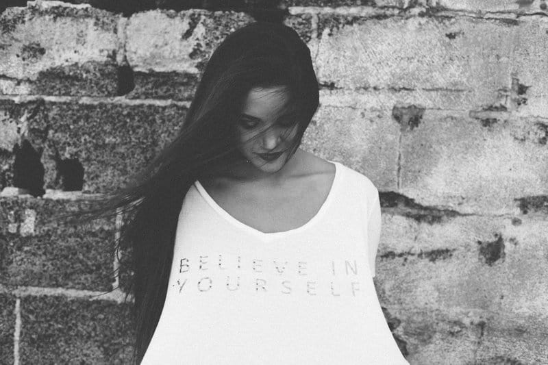 Image of a woman holding a t-shirt that says Believe in Yourself