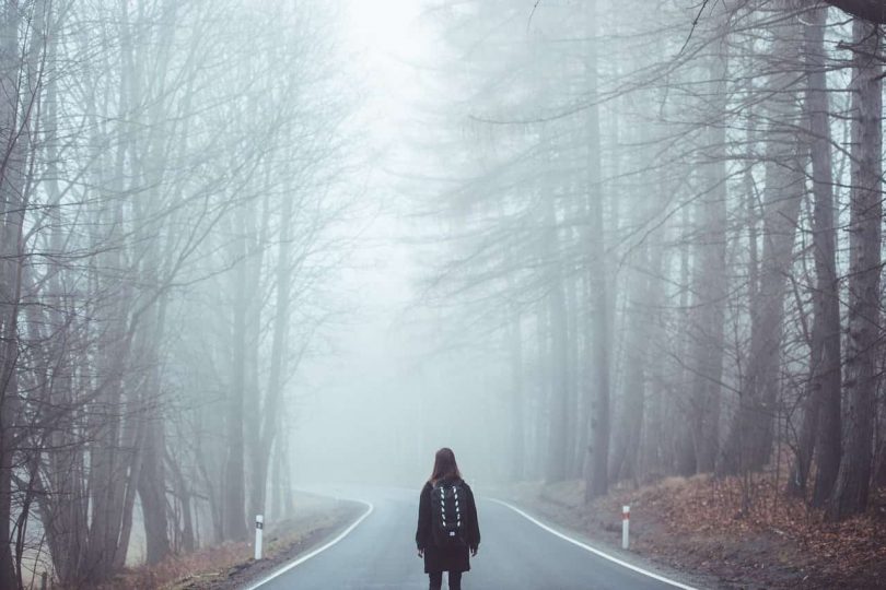 Image of a woman walking down a road in a forest