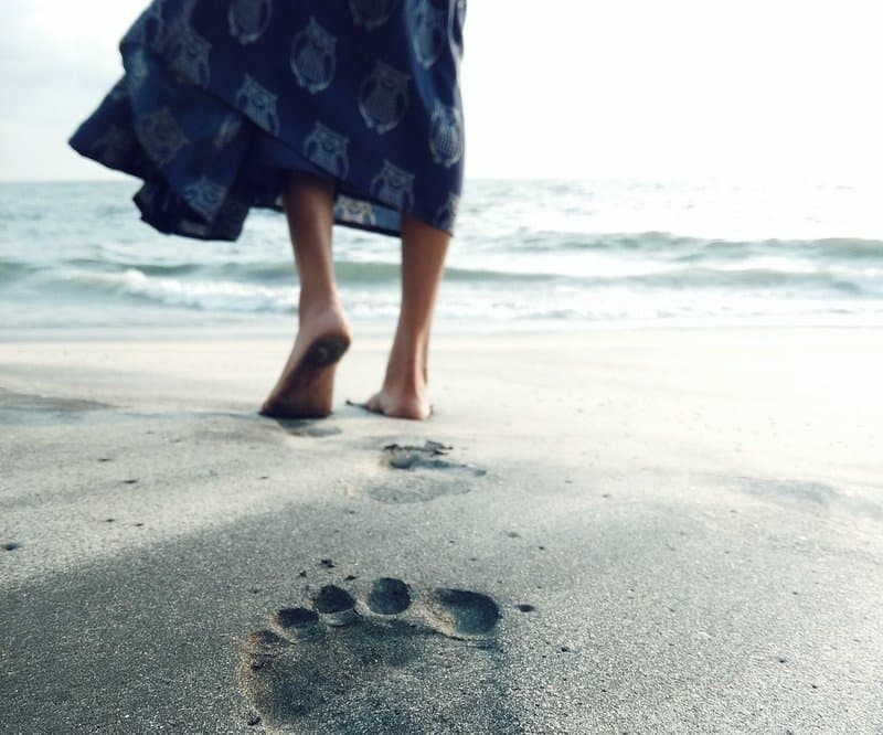 Image of a woman walking on the beach grounding herself