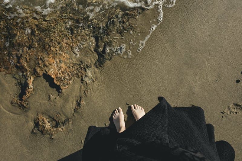 Image of a woman's feet on the beach near the water