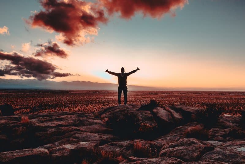 Image of a man at sunset with his arms opened wide