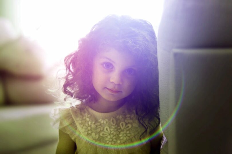 Image of a curious little girl with the sun behind her symbolic of the inner child