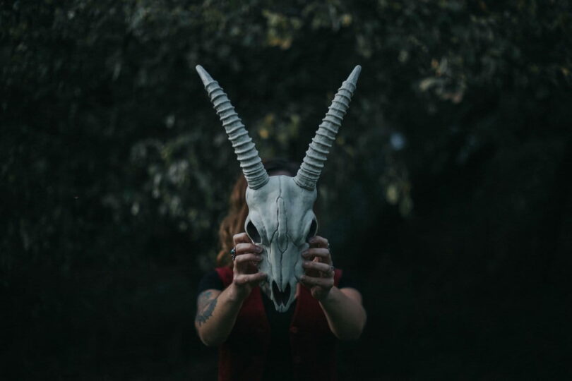 Image of a woman holding up an animal skull symbolic of the collective shadow