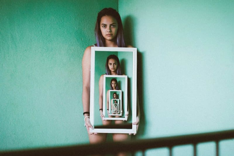 Image of a woman holding up a mirror symbolic of collective shadow work