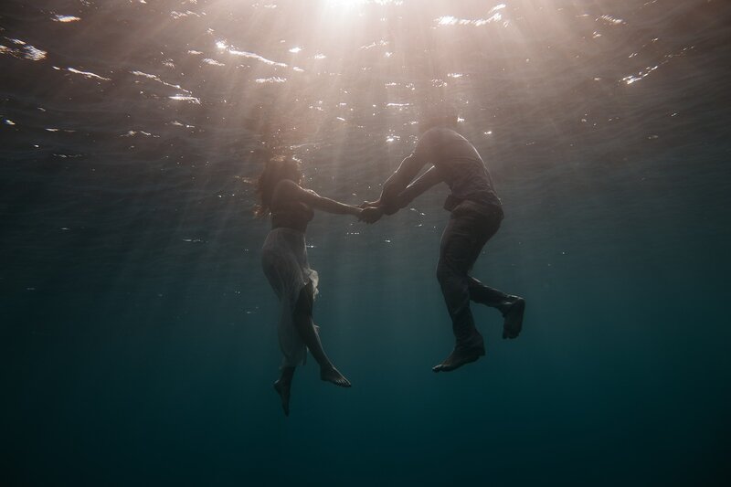 Image of two people holding hands stranded in the ocean