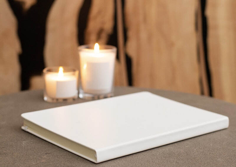 Image of a white journal on a table with candles in the background