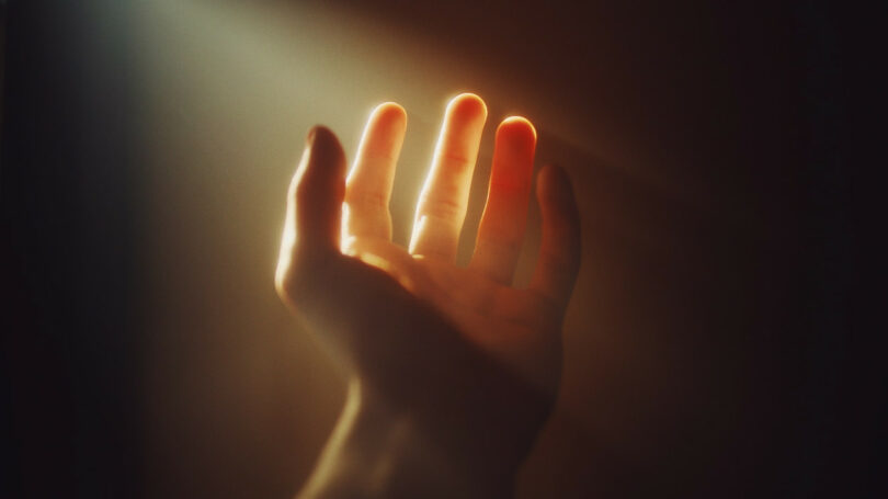 Image of a hand reaching to the light symbolic of spiritual enlightenment