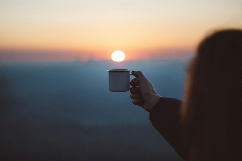 Image of a woman raising a cup to the sun