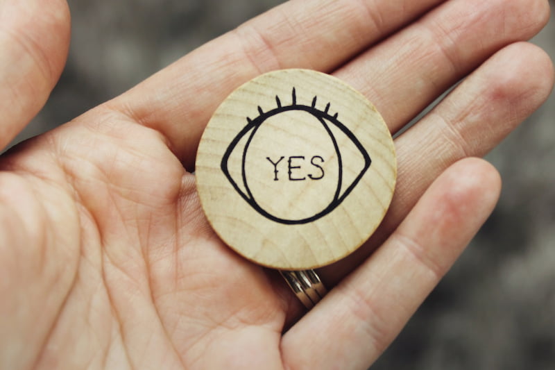 Image of a person holding an object that says yes