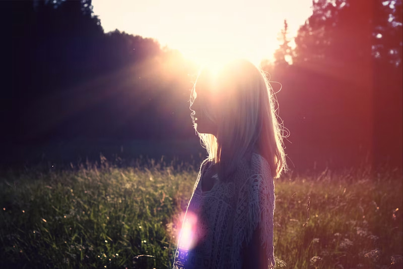 Image of a woman experiencing ensoulment with the sun shining on top of her