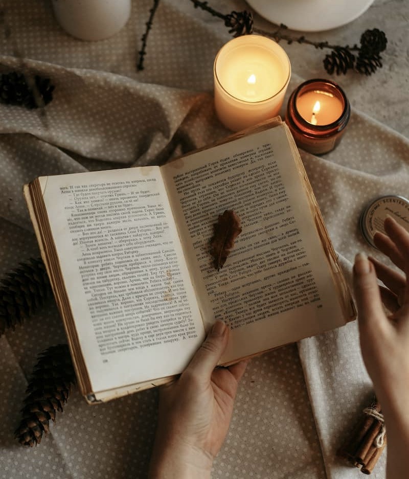 Image of a person reading a book with candles