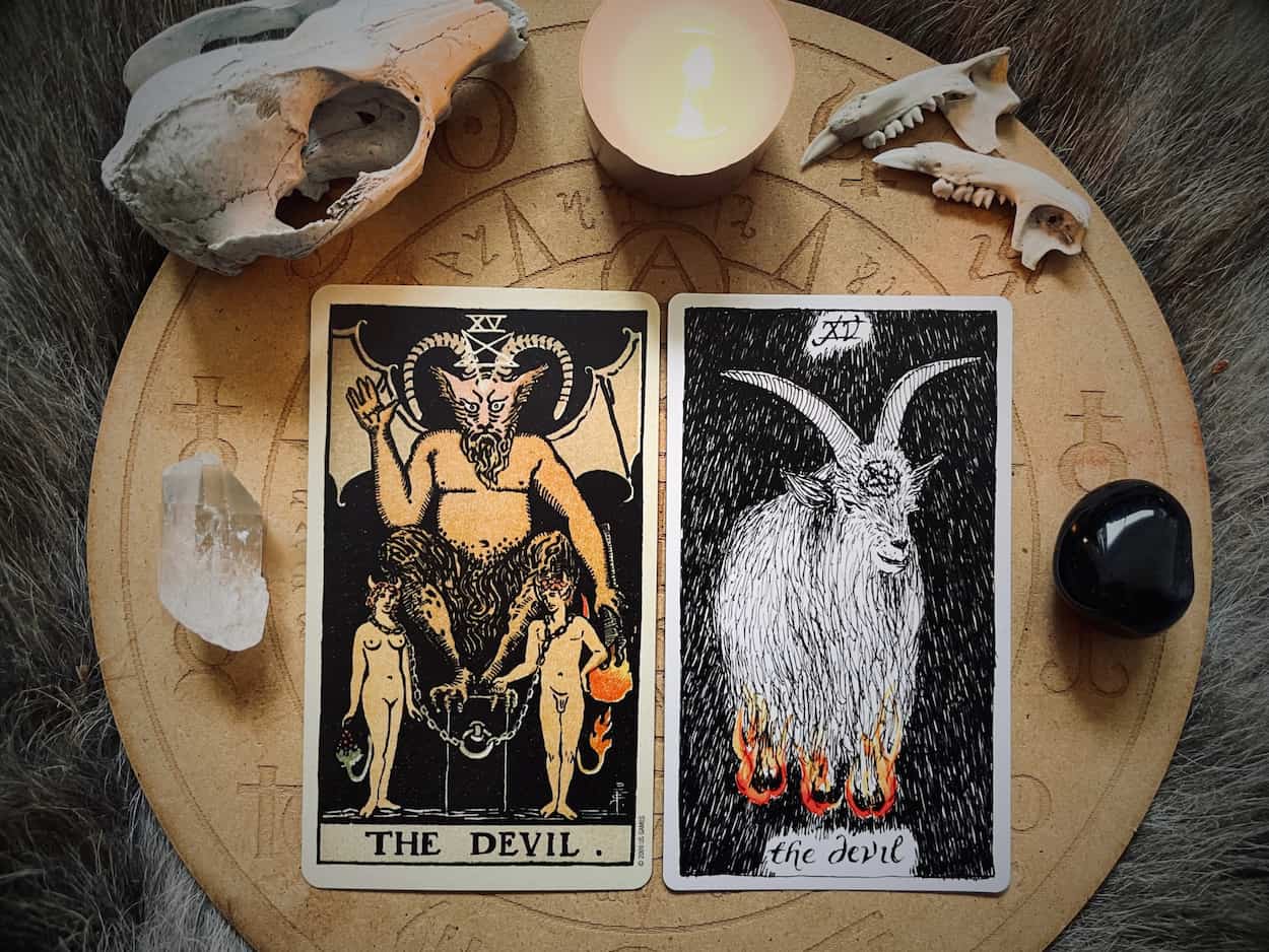 Image of the devil card from the tarot surrounded by stones and bones symbolic of tarot shadow work