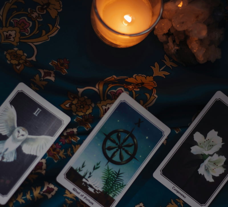 Image of cards used for tarot shadow work on a table with a candle