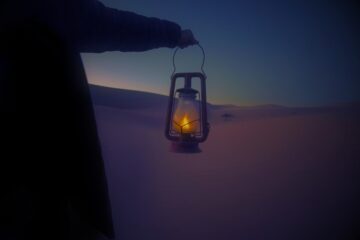 Image of a person holding a lantern in the desert symbolic of undergoing a spiritual journey of inner soul work and ensoulment
